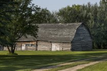 Une grange en rondins aux murs inclinés et au toit abîmé ; Manitoba, Canada — Photo de stock