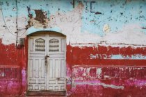 Facciata indossata e intemperie di un edificio con vernice peeling e doppie porte; Nicaragua — Foto stock