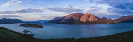 La luz del anochecer ilumina las montañas que rodean el lago Tagish en el Yukón; Carcross, Territorio del Yukón, Canadá - foto de stock