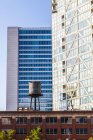 Gebäude in der Innenstadt Chicagos mit einem Wasserreservoir auf dem Dach eines Wohnhauses, das den Kontrast zwischen alten und neuen Gebäuden zeigt; Chicago, illinois, United States of America — Stockfoto