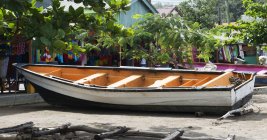 Barco de pesca amarrado cerca de la tienda que vende ropa de colores en el Caribe; Anse La Raye, Santa Lucía - foto de stock