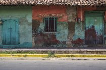 Façade usée et altérée d'un bâtiment avec peinture écaillée et portes doubles ; Nicaragua — Photo de stock