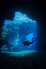 Plongeur sous-marin nage à travers des arcs de lave avec des rayons du soleil, site de plongée cathédrales ; Lanai City, Lanai, Hawaï, États-Unis d'Amérique — Photo de stock
