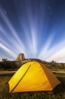 Bright yellow tent and star trails, Devils Tower National Monument; Wyoming, United States of America — Stock Photo