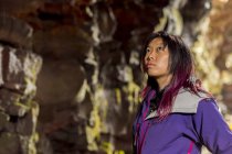 Seitenprofil Nahaufnahme einer asiatischen Wanderin, die an den Höhlenwänden in einer Lava-Röhrchen-Höhle in Island nach oben blickt — Stockfoto