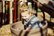 Cute young girl spinning in a saucer on a playground — Stock Photo