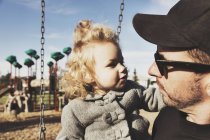 Linda chica joven con padre después de jugar en un parque infantil - foto de stock