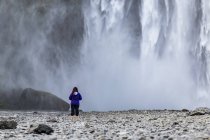Vista traseira do turista feminino ao lado da cachoeira Skogafoss, Islândia — Fotografia de Stock