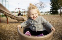 Nettes junges Mädchen, das sich auf einem Spielplatz in einer Untertasse dreht — Stockfoto