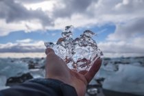 Imagen recortada del hombre sosteniendo un trozo de hielo en Jokulsarlon, Islandia - foto de stock