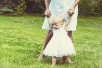 Cropped image of little baby girl walking in park with mother — Stock Photo