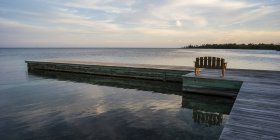 Wooden bench on a dock facing the coastline and open ocean at sunrise, Belize — Stock Photo