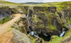 Female tourist standing on a cliff viewpoint in the picturesque valley of Fjadrargljufur, Iceland — Stock Photo