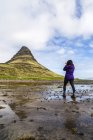 Visão traseira do caminhante feminino tirando foto com câmera na frente da Montanha Kirkjufell, Islândia — Fotografia de Stock