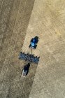 Vista aérea de un tractor tirando de una sembradora de aire, sembrando un campo - foto de stock