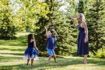 Mother blowing bubbles for kids while on in park — Stock Photo