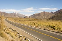 Route mène l'oeil à travers le désert et les montagnes enneigées, Malargue, Mendoza, Argentine — Photo de stock