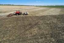 Trattore tirando un air seeder, seminando un campo con cielo blu in lontananza — Foto stock
