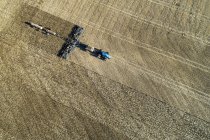 Aerial view of a tractor pulling an air seeder, seeding a field — Stock Photo
