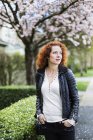 Porträt einer Frau mit roten, lockigen Haaren, die im Frühling draußen spazieren geht — Stockfoto