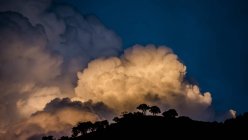 Nuvens a brilhar ao pôr-do-sol sobre árvores silhuetas e colinas, Utah, EUA — Fotografia de Stock