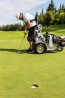 Інвалідів гольфіст шикуються його застрелили перед надягаючи м'яч гольф зелений і за допомогою спеціалізованих гольф допомоги моторизовані гідравлічні візку, Едмонтон, Альберта, Канада — стокове фото