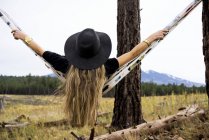 Visão traseira de uma mulher sentada em uma rede com vista para uma montanha, Arizona, Estados Unidos da América — Fotografia de Stock