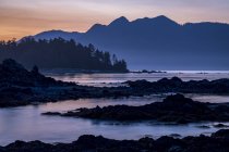 El atardecer cae sobre la isla de Vancouver vista desde un islote en el Parque Provincial Nuchatlitz, Columbia Británica, Canadá - foto de stock