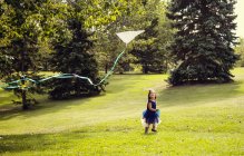 Молодая девушка в платье бегает и запускает воздушного змея в парке — стоковое фото