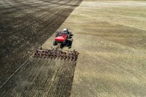 Aerial view of a tractor pulling an air seeder, seeding a field — Stock Photo