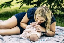 Junge Mutter spielt mit ihrem Baby auf einer Decke im Stadtpark — Stockfoto