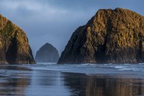 Haystack Rock and other sea stacks seen on Crescent Beach, Cannon Beach, Орегон, США — стоковое фото