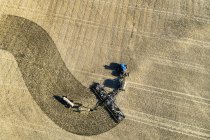 Luftaufnahme eines Traktors, der eine Sämaschine zieht und ein Feld aussät — Stockfoto
