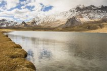 Lago montês desolado visto da costa com as montanhas cobertas com uma camada de neve fresca, Malargue, Mendoza, Argentina — Fotografia de Stock