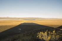 La puesta de sol detrás de un volcán crea una larga sombra sobre el desierto, Malargue, Mendoza, Argentina - foto de stock
