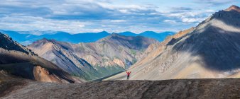 Woman standing with her arms raised while on a ridge line in Kluane National Park and Reserve; Haines Junction, Yukon, Canada — Stock Photo