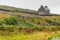 Alleinstehendes Haus in einer abschüssigen Landschaft, Westküste Irlands an der Mündung der Galway Bay, Inishmore, Aran Islands; Kilronan, County Galway, Irland — Stockfoto