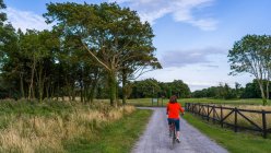 Woman riding her bike down a road at Gleno Abbey Hotel and Golf Course; County Galway, Ireland — Stock Photo