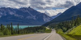Road through the rugged Canadian Rocky Mountains with a turquoise alpine lake and forests; Clearwater County, Alberta, Canadá — Fotografia de Stock