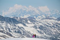 Paar beim Wandern auf einem Berggipfel mit den massiven Bergen des Kluane National Park und Reserve in der Ferne; Haines Junction, Yukon, Kanada — Stockfoto