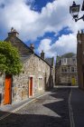 Case con porte colorate e luminose lungo una strada lastricata di settetti; St Andrews, Fife, Scozia — Foto stock