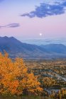 Vue de la lune se levant au-dessus de Palmer et de la rivière Knik depuis le sommet de la Butte, les montagnes Chugach en arrière-plan pendant le crépuscule par une soirée claire, centre-sud de l'Alaska, Palmer, Alaska, États-Unis d'Amérique — Photo de stock