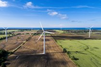Grandi turbine eoliche in fattoria si riempie con un lago sullo sfondo e cielo blu con nuvole, a ovest di Port Colborne; Ontario, Canada — Foto stock