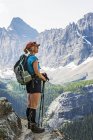 Escursionista donna in piedi sul bordo della scogliera che domina le montagne e la valle; British Columbia, Canada — Foto stock