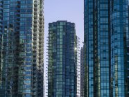 Condominios de rascacielos con fachada de vidrio que refleja el cielo azul; Vancouver, Columbia Británica, Canadá - foto de stock