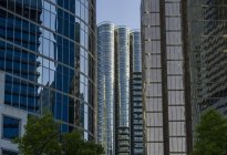 Edifícios de escritórios de arranha-céus e condomínios com fachadas de vidro que refletem o céu azul e edifícios adjacentes; Vancouver, British Columbia, Canadá — Fotografia de Stock