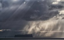 Dramáticas nubes de tormenta y luz sobre una isla frente a la costa de Islandia; Islandia - foto de stock