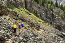 Un groupe de marcheuses le long d'un sentier de montagne rocheux avec des falaises rocheuses à l'arrière-plan ; Colombie-Britannique, Canada — Photo de stock