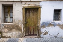 Деревянная дверь и выветриваемая стена на доме; Сеговия, Кастилия и Леон, Испания — стоковое фото