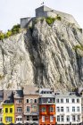 Farbenfrohe Gebäude mit steilen Klippen und mittelalterlicher Festung auf dem Gipfel; Dinant, Belgien — Stockfoto